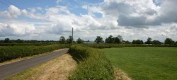 Looking south east along Welshmen's Lane towards Nantwich, with the tower of the town's church visible on the horizon. This may be one of the narrow winding hedged lanes along which Fairfax's troops were marching when they came under royalist attack.